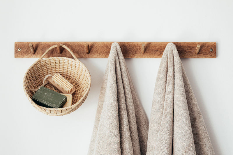 Basket with natural soap and brush and beige towels hanging